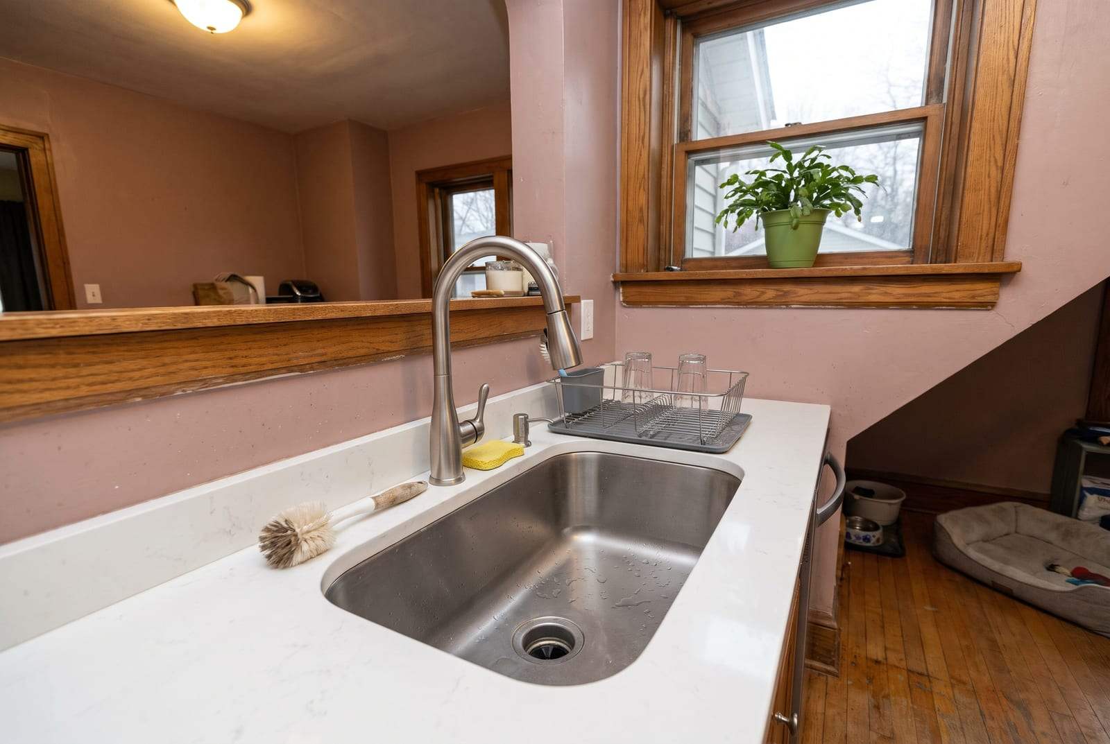 Brushed nickel kitchen faucet over a stainless sink in an older home’s kitchen