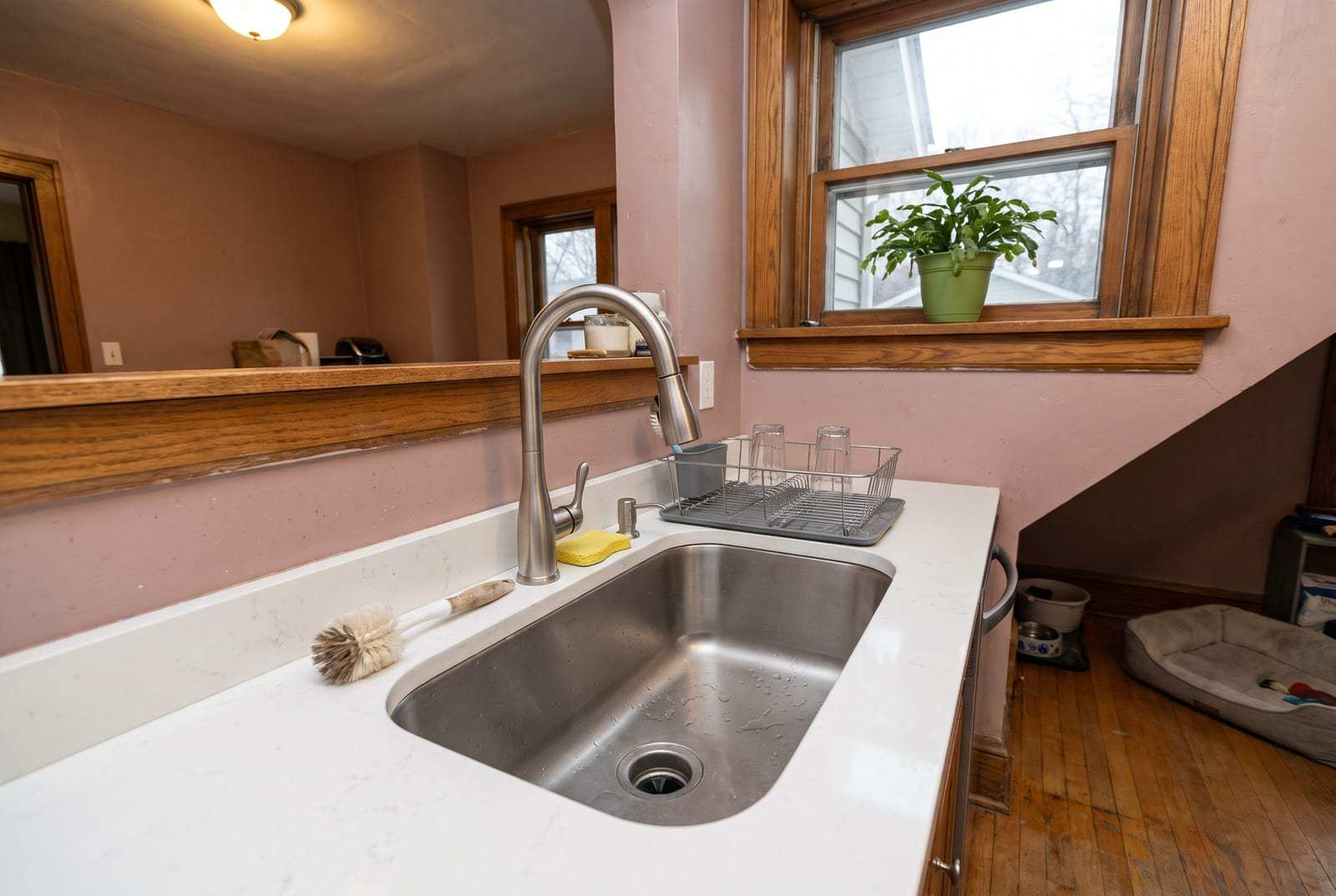 Brushed nickel kitchen faucet over a stainless sink in an older home’s kitchen